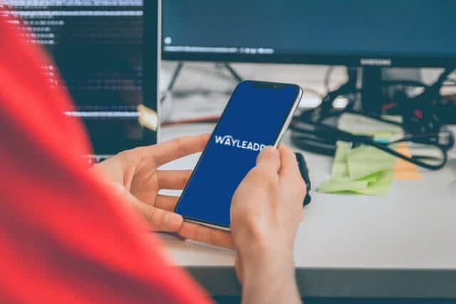Person holding a smartphone displaying the Wayleadr logo