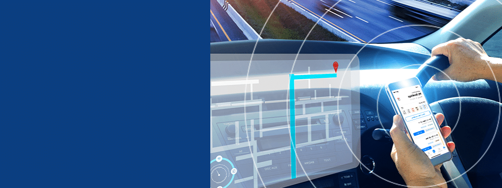 A person is driving a car while holding a smartphone displaying a navigation app, with a digital map shown on the car’s dashboard, guiding them efficiently through the commercial parking area.