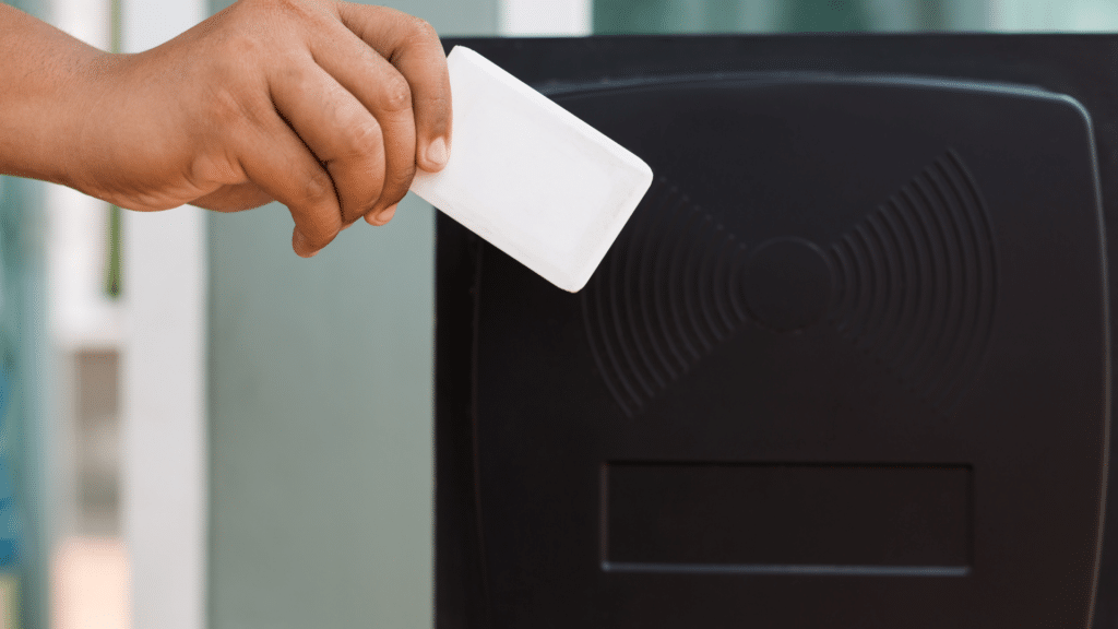 A person is holding a white access card near a black card reader for entry authorization, seamlessly integrating with advanced parking management systems.