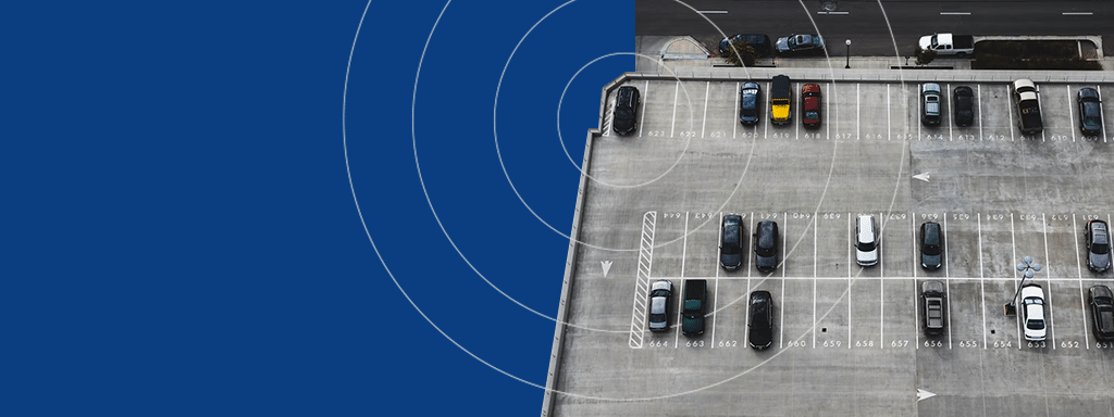 Aerial view of a mostly empty parking lot with several cars parked in marked spaces. A blue overlay with circular patterns covers the left side of the image, emphasizing efficient parking lot systems.