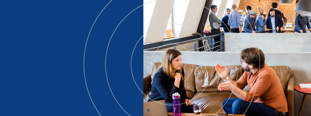 Two people having a discussion on a couch in the foreground, with several individuals in business attire interacting and discussing parking management systems in the background.