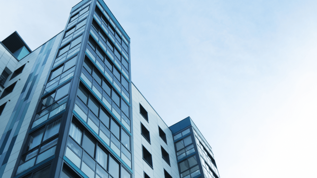 A modern glass-clad high-rise building against a clear blue sky, featuring advanced commercial parking managed by Wayleadr.