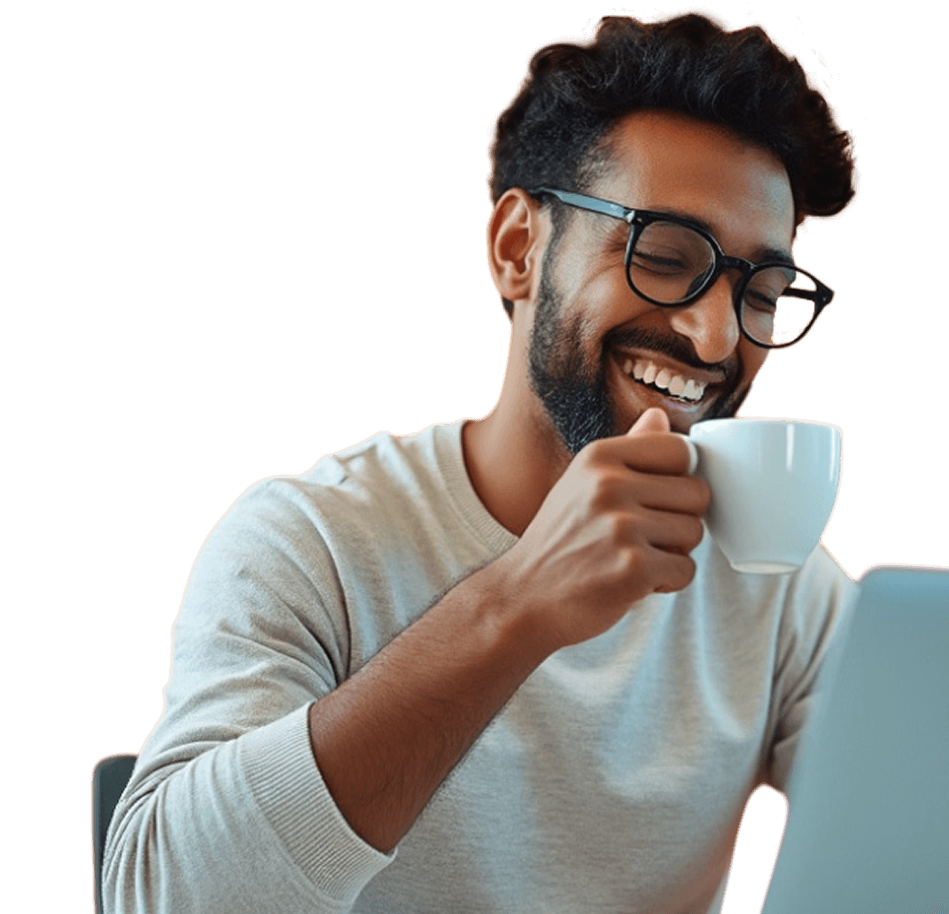 A man wearing glasses, smiling and holding a white coffee cup, looks at a laptop screen.